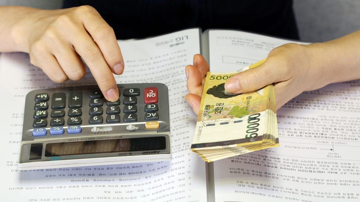 A calculator, a bank passbook, and a stack of banknotes being handed over