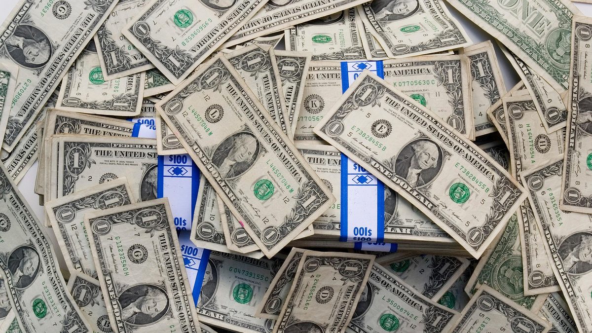 A pile of one-dollar bills, some banded in stacks
